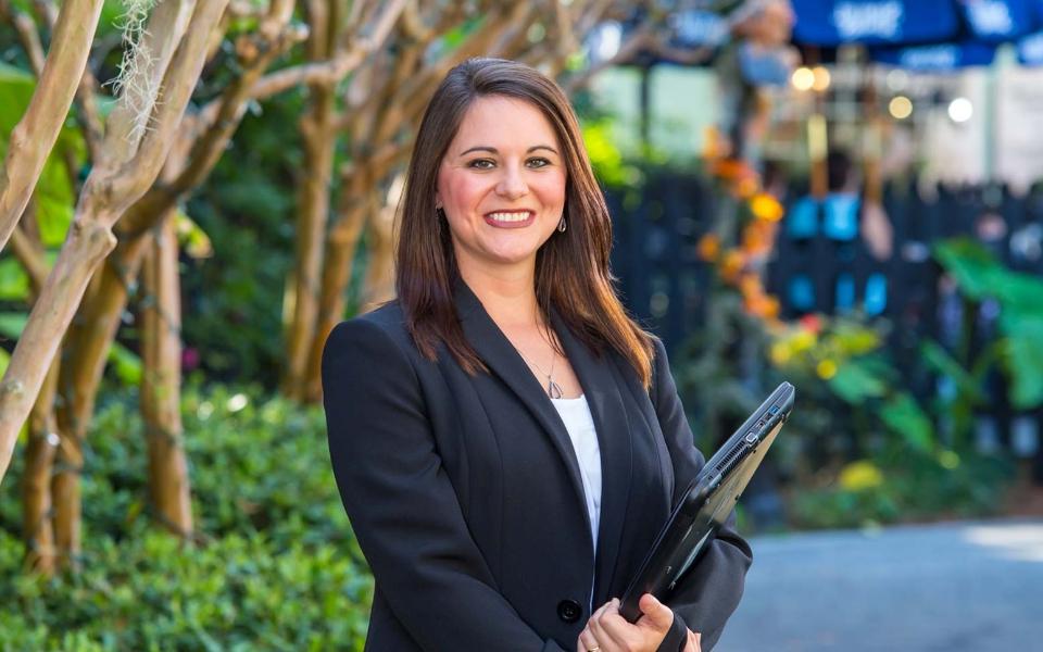 White woman in a business suit holding her laptop